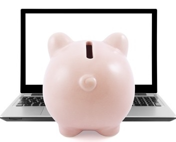Piggy bank in front of a blank laptop