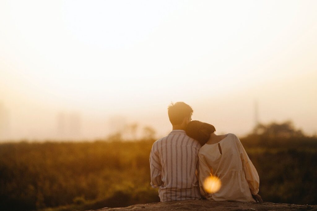 Man and woman couple sitting outside looking at the sunset