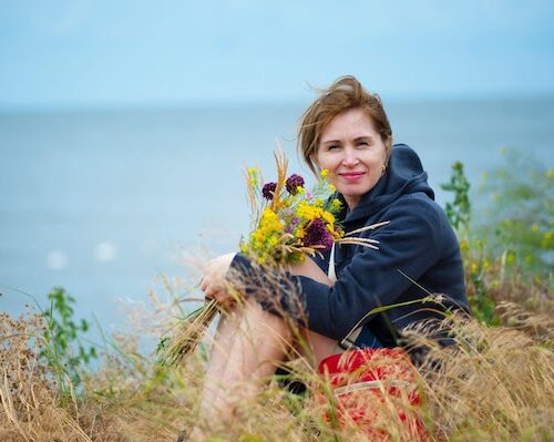woman sitting down in a field above the beach