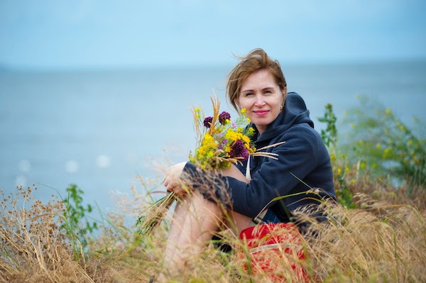 woman sitting down in a field above the beach