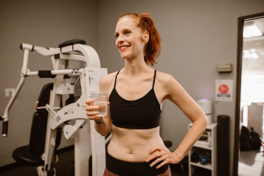 Woman over age 35 in the gym drinking a glass of water