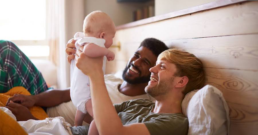 happy gay couple in California holding their newborn baby